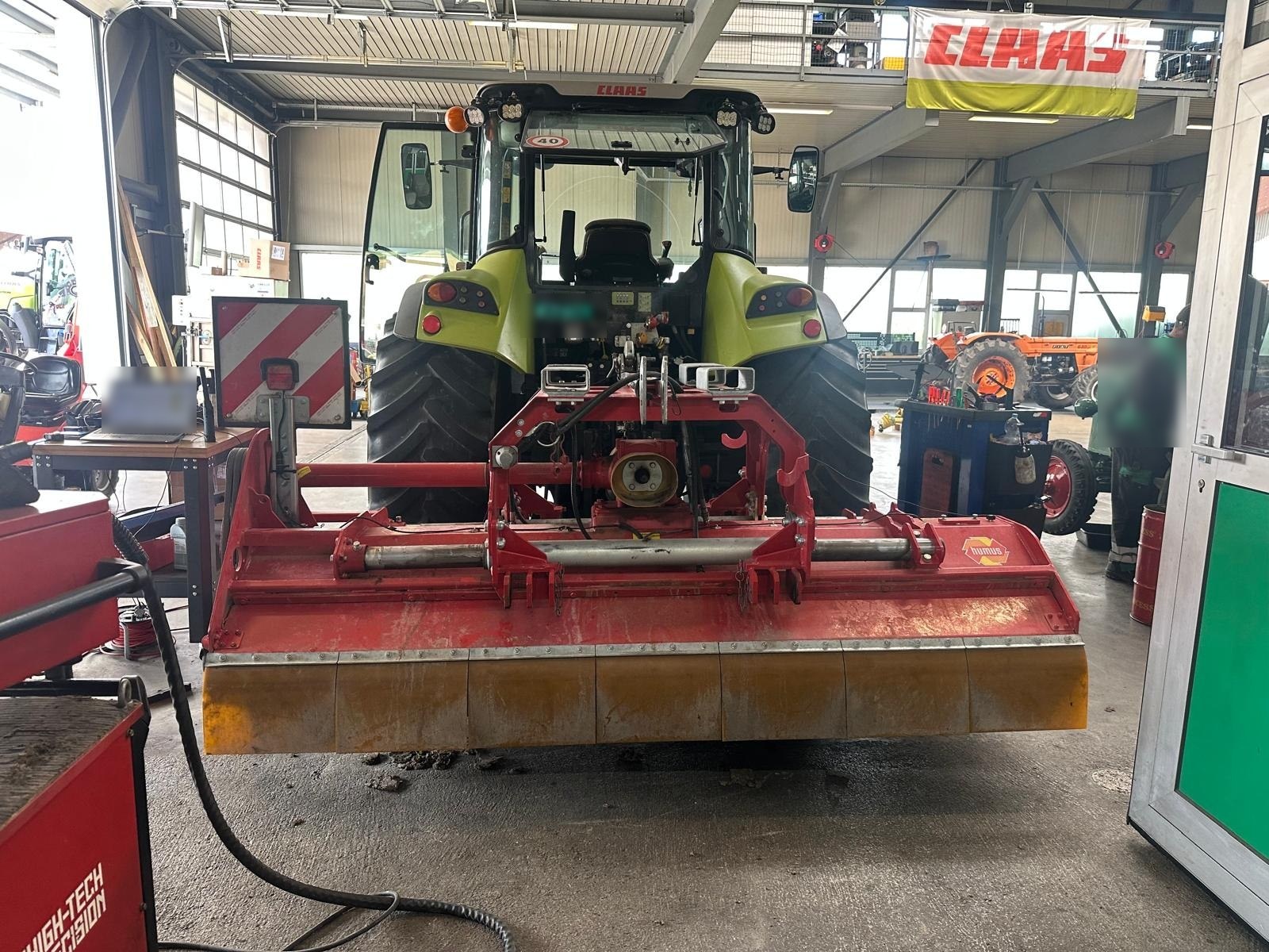 Flail mulcher mounted on a tractor in a farm workshop, ready for balancing